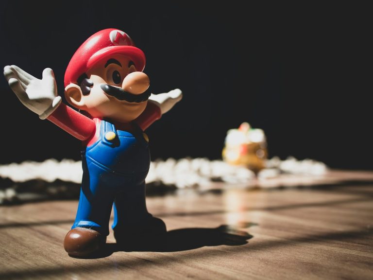 Figurine de Mario avec les bras ouverts, gâteau en arrière-plan.